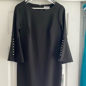 Classic, knee length, Pearl accented tulip sleeves. Concealed back zipper.